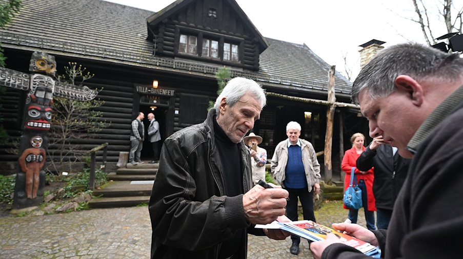 Gojko Mitic (l), deutsch-serbischer Schauspieler und Regisseur, steht im Karl May Museum vor der „Villa Bärenfett“ und gibt Autogramme. / Foto: Sebastian Kahnert/dpa