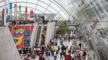 Besucherinnen und Besucher gehen am zweiten Messetag durch die Glashalle der Leipziger Buchmesse. / Foto: Jan Woitas/dpa
