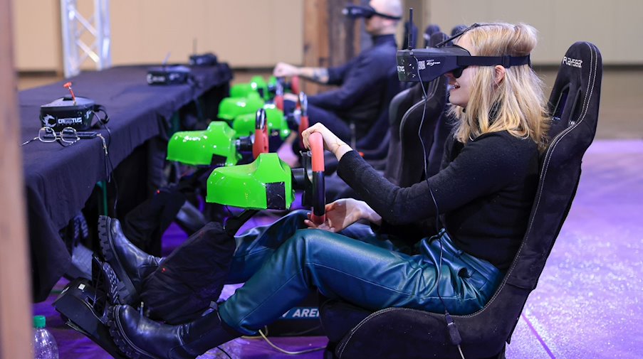 Zwei Besucher des Gamingfestival «CAGGTUS» testen das Fahren und Steuern ferngesteuerter Autos mit einer VR-Brille auf der Leipziger Messe. / Foto: Jan Woitas/dpa/Archivbild