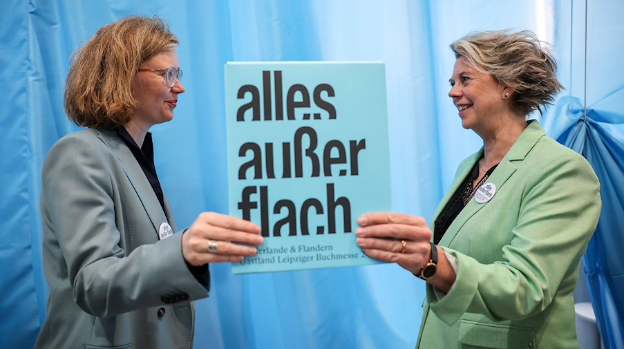 Die Kuratorinnen Bettina Baltschev (l) und Margot Dijkgraaf stehen mit dem Motto des Gastlandes 2024 „alles außer flach“ auf der Leipziger Buchmesse. / Foto: Jan Woitas/dpa