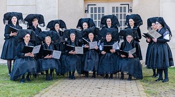 Frauen der Chorgemeinschaft Concordia singen in schwarzen Trachten am Ostersonntag vor der evangelischen Kirche im Spreewaldort Burg. / Foto: Frank Hammerschmidt/dpa/Archivbild