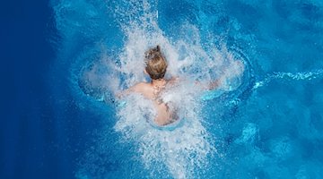 Ein Junge springt in einem Freibad ins Wasser. / Foto: Joerg Carstensen/dpa/Symbolbild