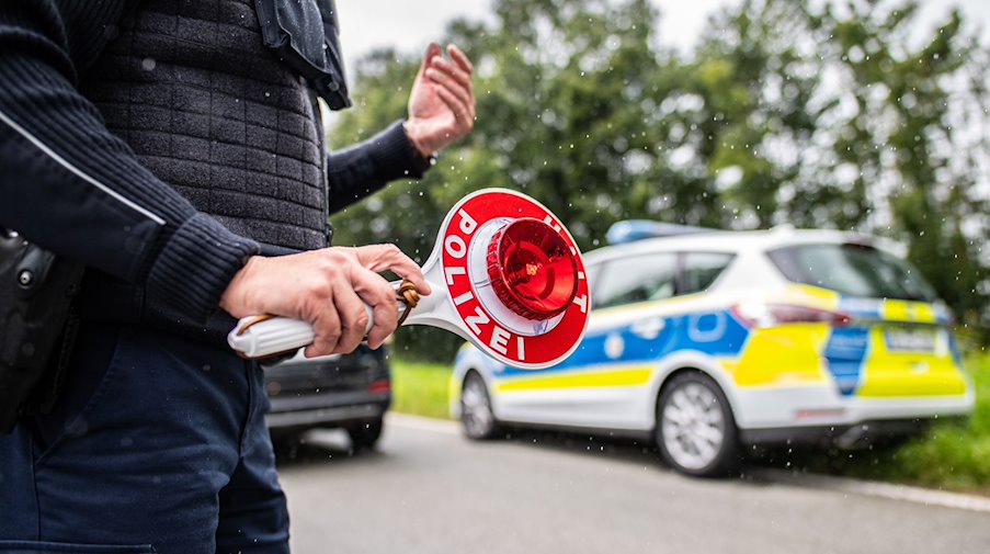 Eine Polizistin hält eine Winkerkelle in der Hand. / Foto: Guido Kirchner/dpa/Symbolbild
