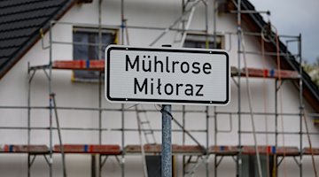 Eine Ortstafel Mühlrose steht vor dem Neubau eines Hauses im sogenannten Neu-Mühlrose in Schleife im Landkreis Görlitz. / Foto: Robert Michael/dpa