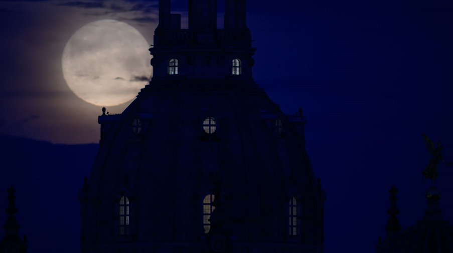 Der Mond geht am Morgen hinter der Frauenkirche unter. / Foto: Robert Michael/dpa