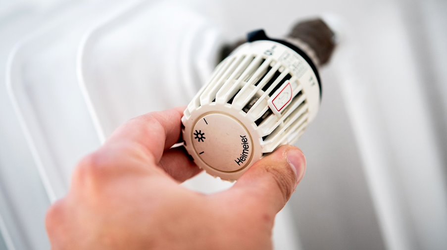 Ein Mann dreht am Thermostat einer Heizung. / Foto: Hauke-Christian Dittrich/dpa/Symbolbild