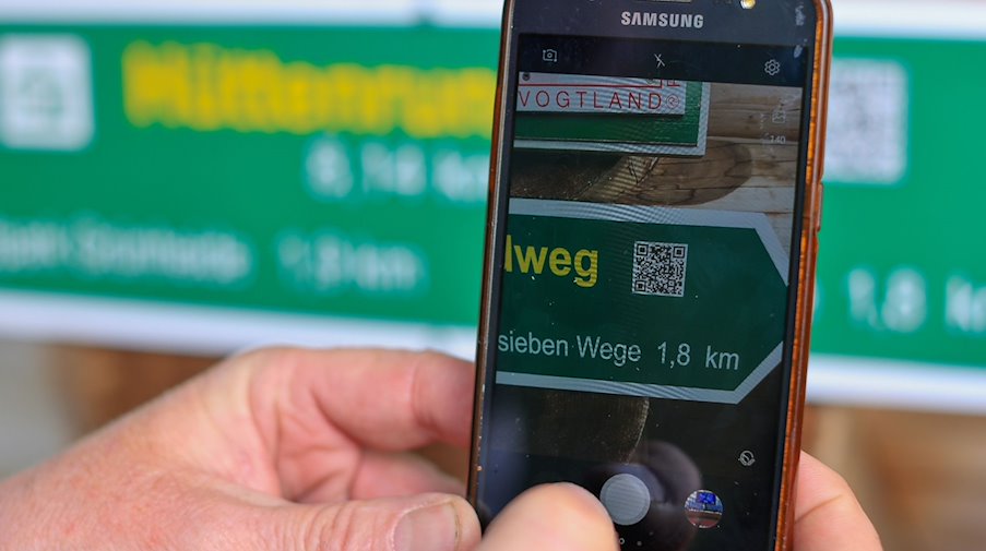 Thomas Putz, Regionalwegewart für den Bereich südöstliches Vogtland, scannt den QR-Code für einen Wanderweg. / Foto: Jan Woitas/dpa