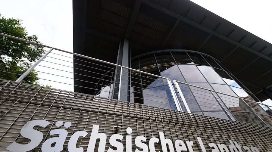 Sächsischer Landtag steht an einem Gitter am hintern Teil des Parlamentsgebäudes. / Foto: Robert Michael/dpa-Zentralbild/dpa