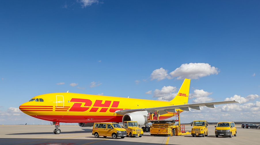 Ein Frachtflugzeug von DHL und verschiedene Fahrzeuge für die Logistik stehen auf dem Vorfeld auf dem Flughafen Leipzig/Halle. / Foto: Jan Woitas/dpa-Zentralbild/dpa