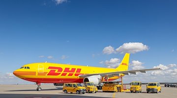 Ein Frachtflugzeug von DHL und verschiedene Fahrzeuge für die Logistik stehen auf dem Vorfeld auf dem Flughafen Leipzig/Halle. / Foto: Jan Woitas/dpa-Zentralbild/dpa