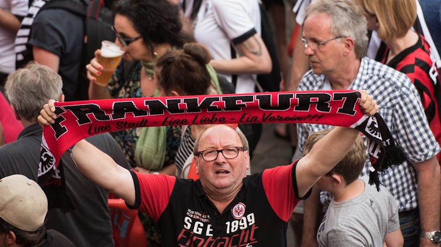 Ein Fan hält einen Eintracht-Schal nach oben. / Foto: Andreas Arnold/dpa/Archivbild