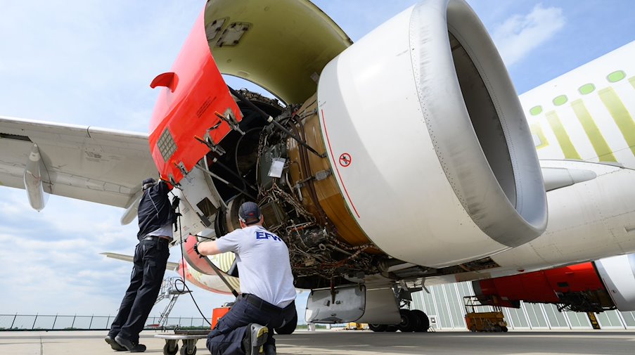 Employees of EFW Elbe Flugzeugwerke GmbH work on the engine of an Airbus A330. / Photo: Robert Michael/dpa