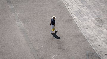 Ein Mann geht über den aufgeheizten Asphalt. / Foto: Frank Rumpenhorst/dpa/Symbolbild