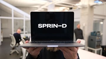 Ein Mitarbeiter der Bundesagentur für Sprunginnovationen hält einen Laptop mit dem Schriftzug. / Foto: Sebastian Willnow/dpa/Illustration