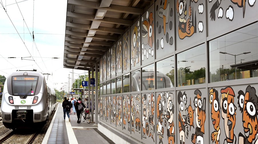 Im Bahnhof Borna fährt eine S-Bahn an einer vom Künstler Michael Fischer-Art bemalten Wand am Bahnsteig 1 vorbei. / Foto: Waltraud Grubitzsch/dpa