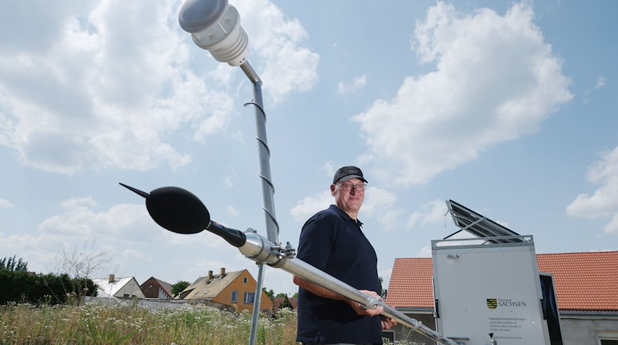 Jörg Puchmüller, Fluglärmschutzbeauftragter des Landes Sachsen, hält den Mast einer mobilen Messstation für Fluglärm. / Foto: Sebastian Willnow/dpa