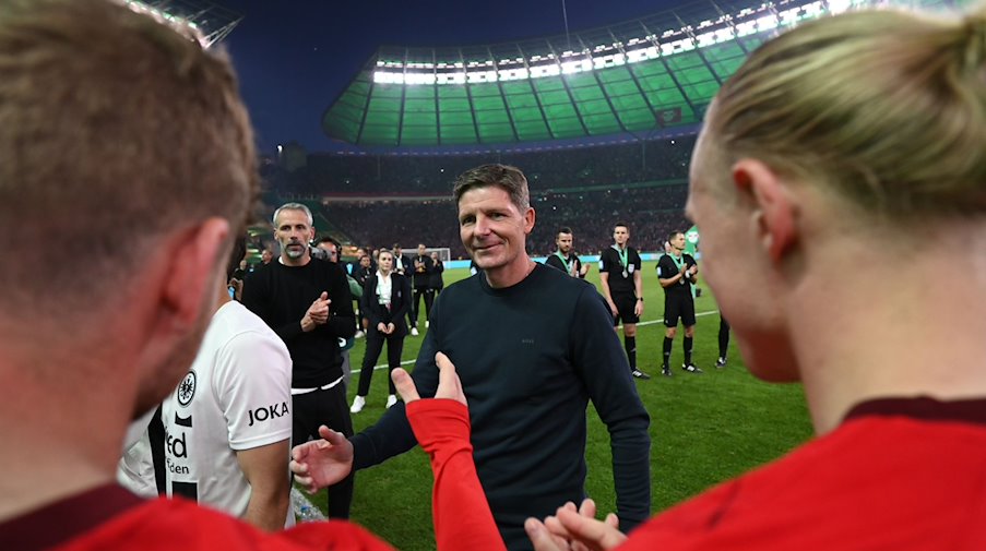 Frankfurts Cheftrainer Oliver Glasner klatscht auf den Weg zur Siegerehrung mit Leipziger Spieler ab. / Foto: Arne Dedert/dpa