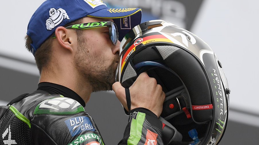 Der deutsche MotoGP Fahrer Jonas Folger vom Monster Yamaha Tech 3 Team freut sich über seinen zweiten Platz und küsst seinen Helm. / Foto: Hendrik Schmidt/dpa