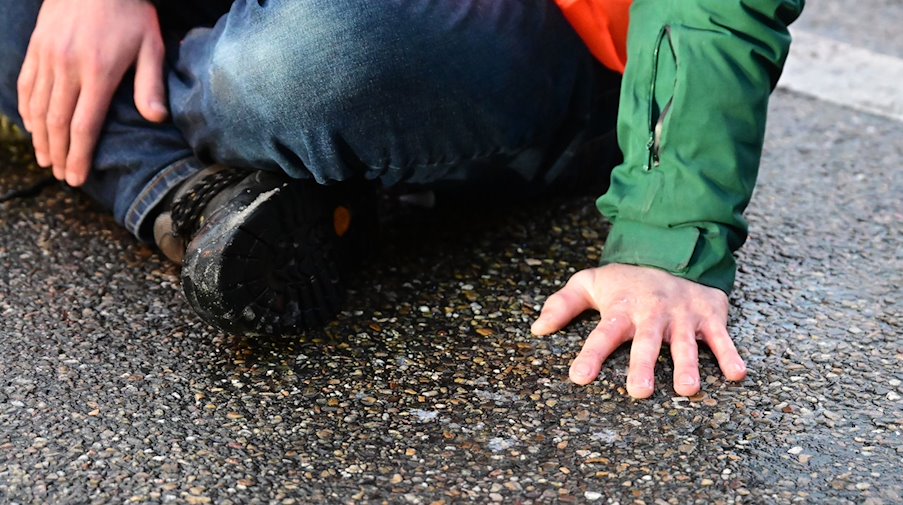 Ein Aktivist hat sich mit einer Hand auf einer Straße festgeklebt. / Foto: Bernd Weißbrod/dpa