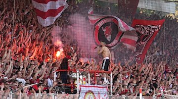 Fans von Union jubeln nach Spielende und zünden Pyrotechnik. / Foto: Soeren Stache/dpa