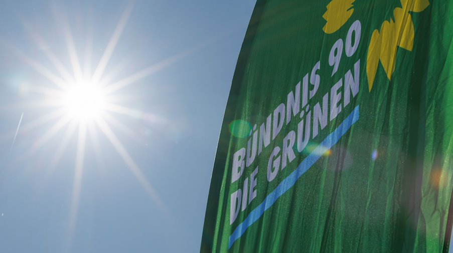 Eine Fahne der Partei Bündnis 90/Die Grünen weht neben der strahlenden Sonne. / Foto: Friso Gentsch/dpa