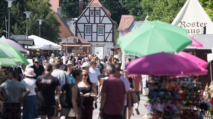 Besucher des Elbhangfests gehen an Verkaufsständen entlang. / Foto: Sebastian Kahnert/dpa-Zentralbild/ZB/Archivbild