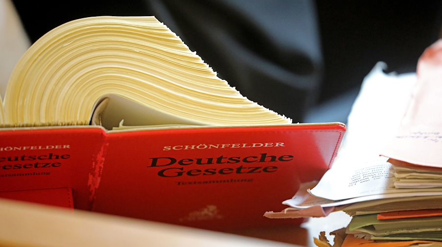 Ein Referendar sitzt im Landgericht vor einem Textband «Deutsche Gesetze». / Foto: Oliver Berg/dpa/Symbolbild