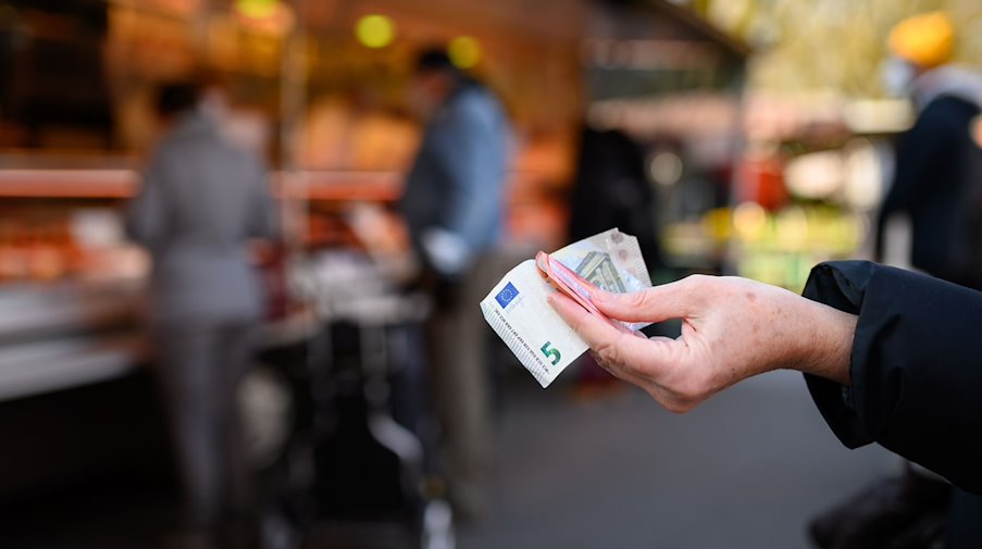 Eine Frau hält das Bargeld für ihren Einkauf in der Hand bereit. / Foto: Jonas Walzberg/dpa/Symbolbild