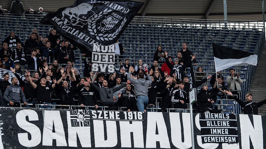 Fans aus Sandhausen stehen mit Flaggen auf der Tribüne. / Foto: Swen Pförtner/dpa/Archivbild