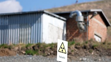 Eine Warnschild «Radioaktivität» steht am Schacht früheren Wismut-Bergbaus in Bad Schlema. / Foto: Sebastian Willnow/dpa