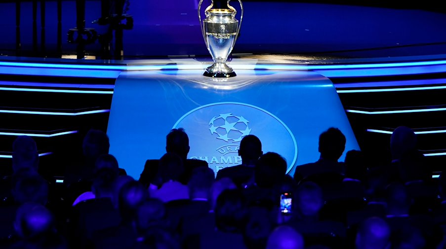 Die UEFA Champions-League-Trophäe steht auf einem Podest vor Beginn der Auslosung. / Foto: Daniel Cole/AP/dpa