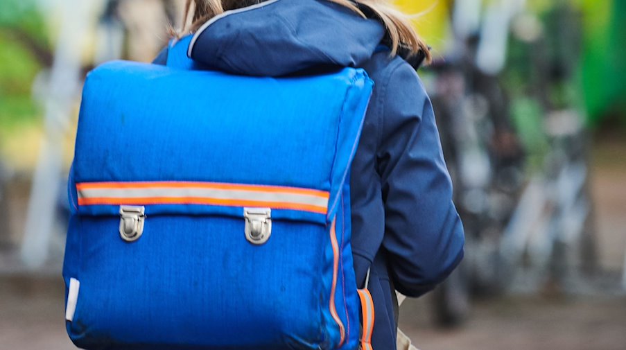 Ein Schüler steht mit Schulranzen nahe einer Grundschule. / Foto: Annette Riedl/dpa/Illustration