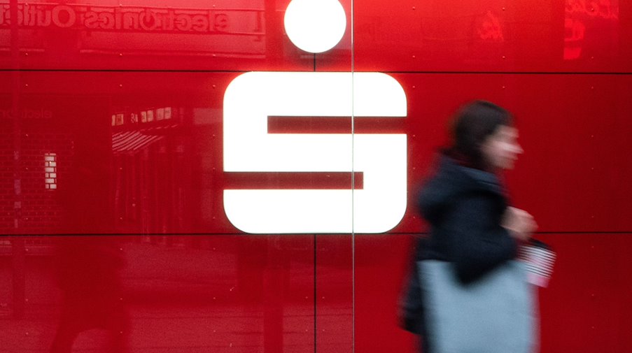 Ein Passantin läuft an einer Sparkasse vorbei. / Foto: Marco Rauch/dpa