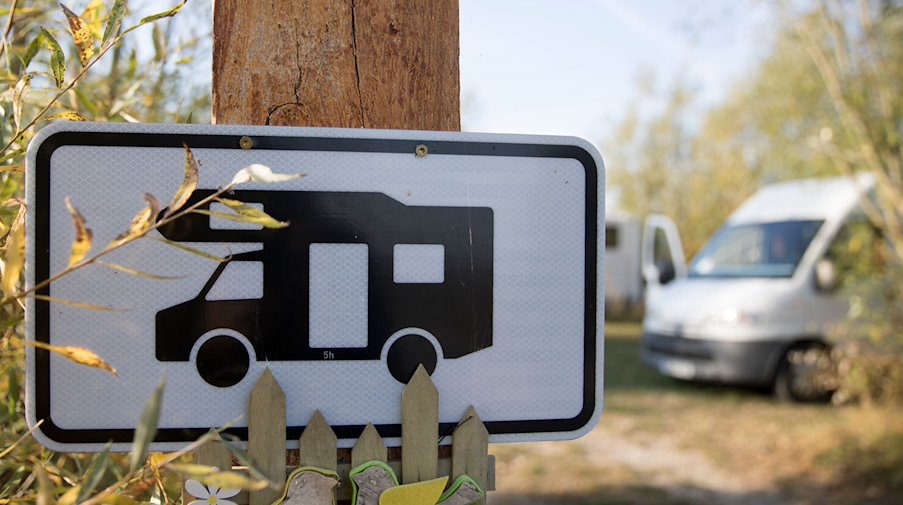 Ein Schild hängt vor einem Stellplatz für Wohnmobile an einem Brett. / Foto: Florian Schuh/dpa-tmn/Symbolbild