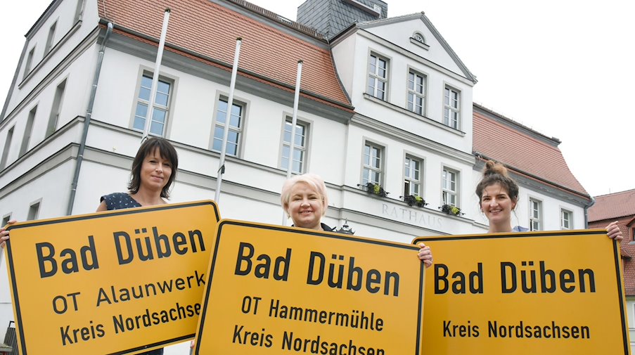 Town entrance signs are held laughing at the camera. / Photo: Waltraud Grubitzsch/dpa