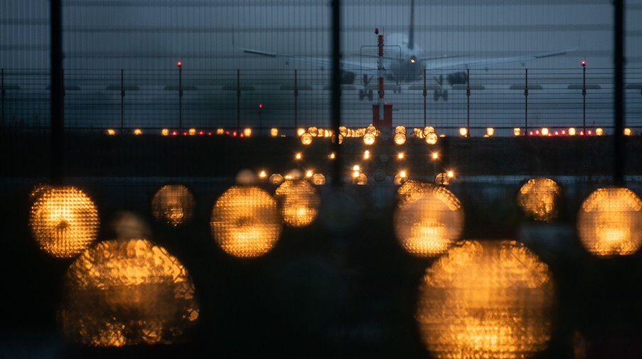 Ein Flugzeug landet hinter Signallichtern auf einem Flughafen. / Foto: Sebastian Gollnow/dpa/Symbolbild