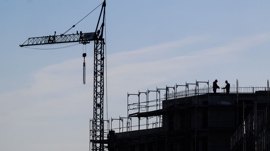 Construction workers stand on the building site of an apartment building. / Photo: Julian Stratenschulte/dpa/Symbolbild