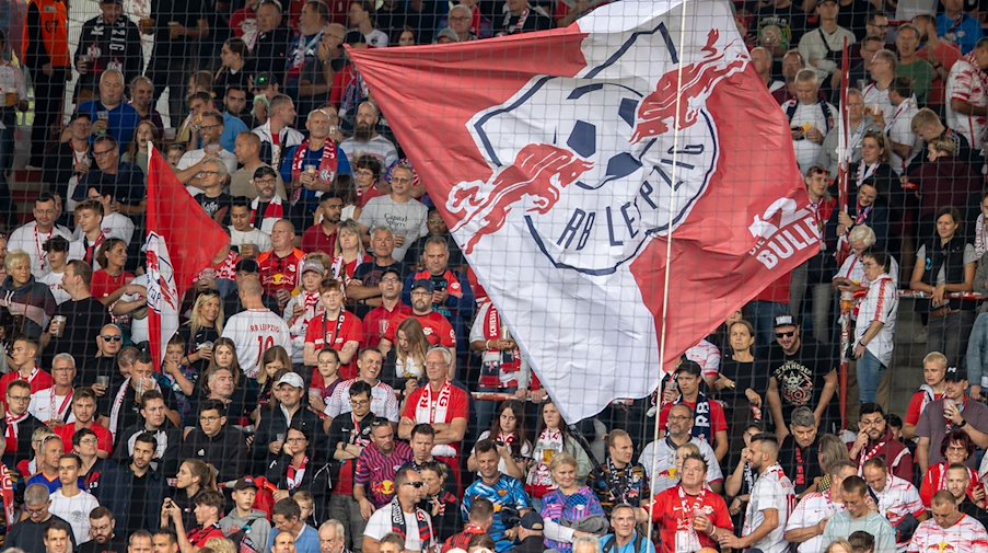Fans von RB Leipzig stehen mit Fahnen im Gästeblock des Stadions. / Foto: Andreas Gora/dpa/Symbolbild