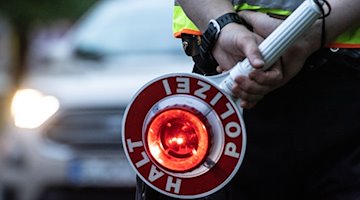 Поліцейський тримає сигнальну лопатку під час регулювання дорожнього руху / Фото: Paul Zinken/dpa/ZB/Symbolbild