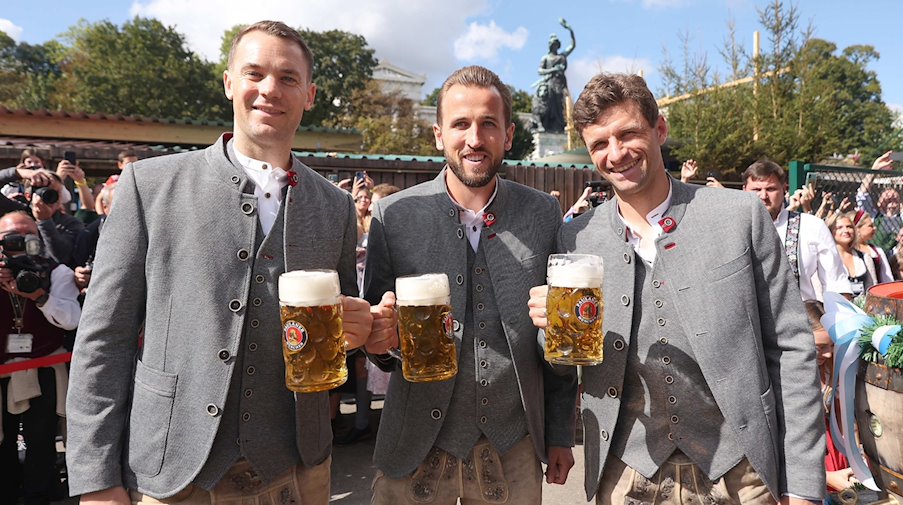 Manuel Neuer (l-r), Harry Kane and Thomas Müller of FC Bayern Munich stand in front of the Käfer tent with a Maß Bier / Photo: Alexander Hassenstein/Getty Images Europe Pool/dpa
