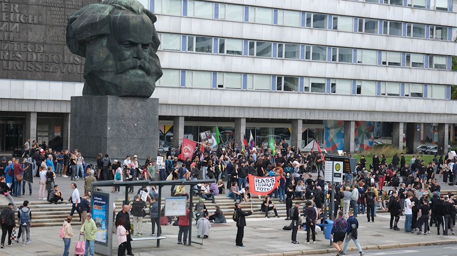 Teilnehmer einer linken Demonstration versammeln sich am Karl-Marx-denkmal. / Foto: Sebastian Willnow/dpa