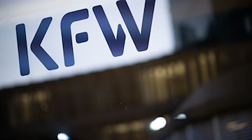 Das Logo der Förderbank KfW steht während einer Pressekonferenz der Förderbank Kreditanstalt für Wiederaufbau (KfW) auf einer Glasscheibe vor Lichtern in Büros. / Foto: Sebastian Christoph Gollnow/dpa