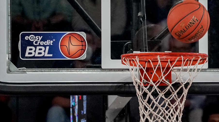 Ein Ball fliegt auf den Korb zu, an dem ein Logo der Basketball-Bundesliga klebt. / Foto: Axel Heimken/dpa/Symbolbild