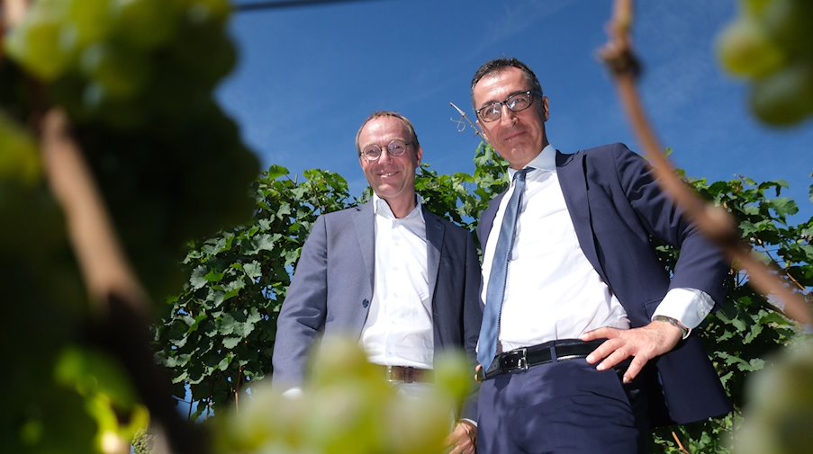 Wolfram Günther (Grüne/ l), Sachsens Landwirtschaftsminister, und Cem Özdemir (Grüne), Bundeslandwirtschaftsminister, stehen an einem Weinstock. / Foto: Sebastian Willnow/dpa