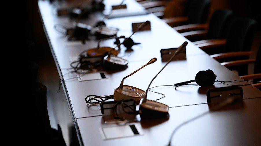Mikrofone und Kopfhörer auf einem Tisch in einem Gerichtssaal. / Foto: Jonas Walzberg/dpa/Symbolbild