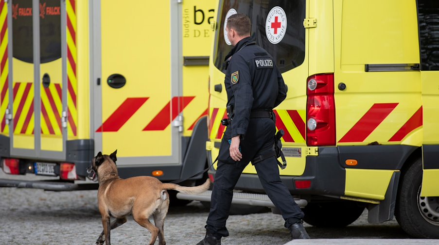 Ein Polizist läuft mit einem Hund vor einer Grund- und Oberschule in Pulsnitz. / Foto: Rocci Klein