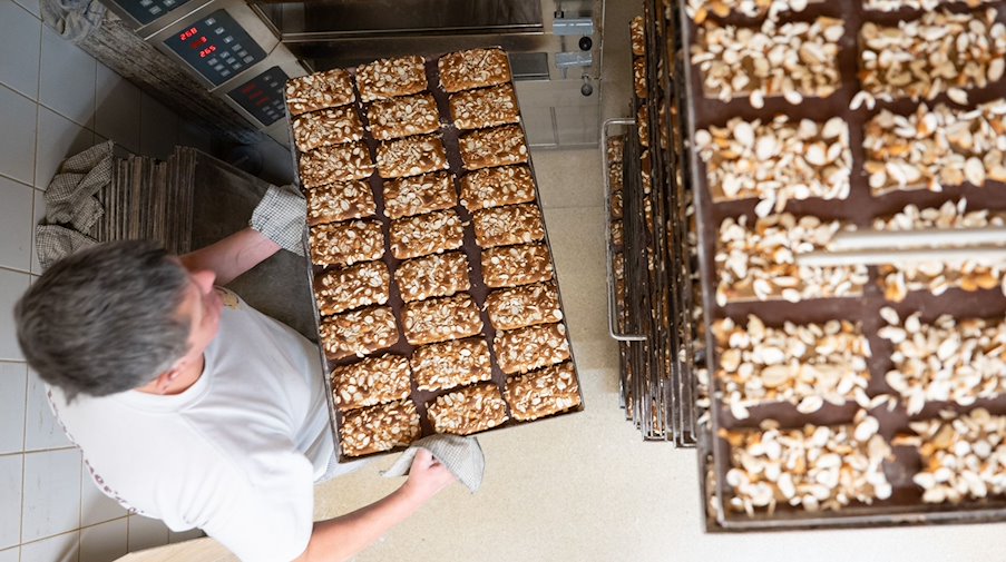 Master gingerbread maker Peter Kotzsch takes a baking tray of gingerbread with slivered almonds out of the oven in the bakery of the Hermann Löschner gingerbread factory / Photo: Sebastian Kahnert/dpa/Archivbild