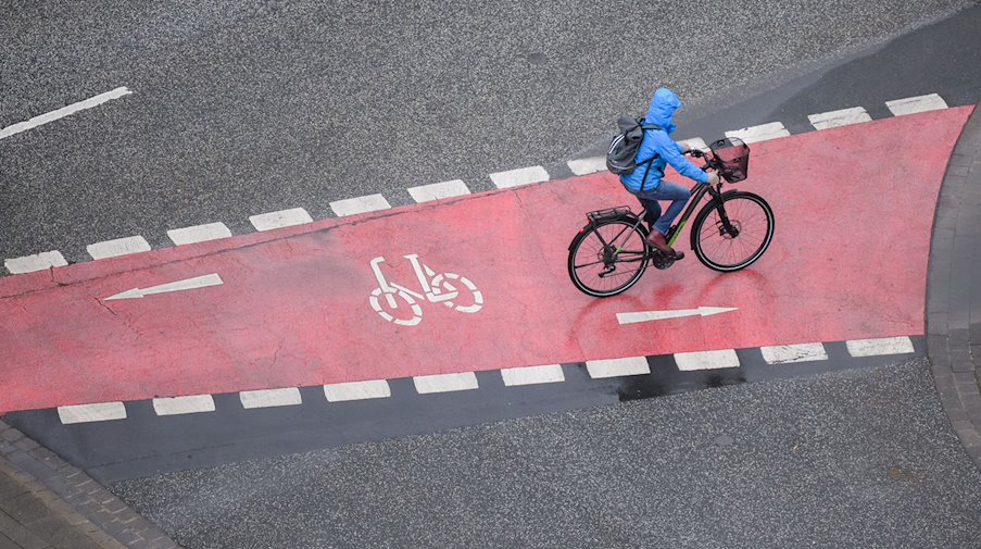 Eine Frau fährt bei Regen mit einem Fahrrad. / Foto: Julian Stratenschulte/dpa/Symbolbild