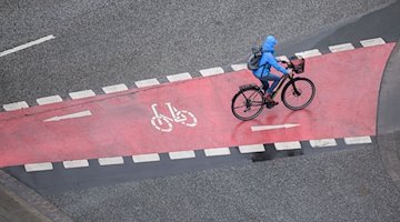 A woman rides a bicycle in the rain / Photo: Julian Stratenschulte/dpa/Symbolbild
