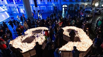 Bürgerinnen und Bürger gestalten im Hof der Nikolaikirche in Lepzig eine 89 aus Kerzen. / Foto: Hendrik Schmidt/dpa